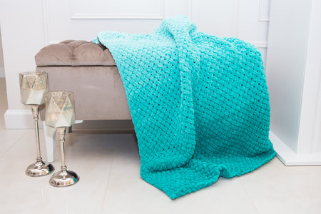 Background texture of plush fabric in aquamarine green color, background pattern of soft woolen material that lies on a small sofa along with candlesticks, cozy conceptの写真素材