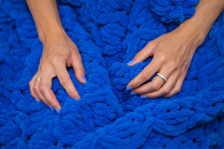 A girl wrapped in a large blue merino wool hand knitted blanket, a warm and very soft blanket, the girl enjoys the softness of the blanketの写真素材