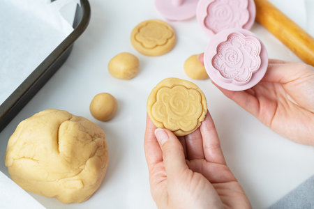 The process of making cookies with shapes in the form of flowers, a rolling pin and a tray, the concept of cooking, baking at homeの写真素材