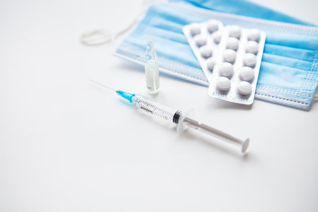 Preparation for vaccination against covid-19. Syringe, vaccine, pills, medical maskの写真素材