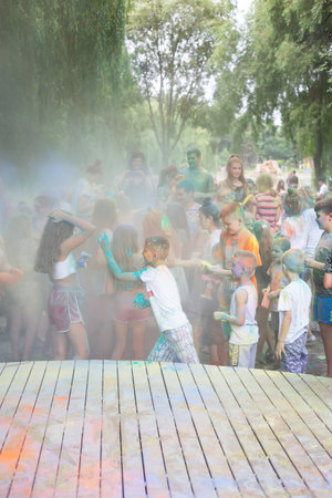 Lviv, Ukraine - July 18, 2021: Color Holi Festival, a crowd of people adults and small children throw colorful paint. Indian holiday, children running on a wooden stageのeditorial素材