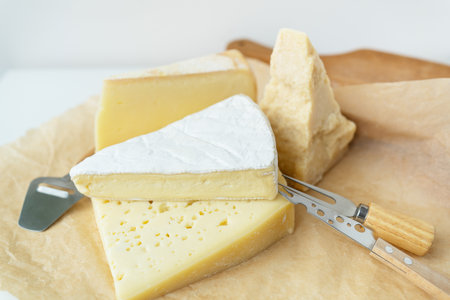Different types of cheese lie on top of each other with cheese knives. A delicious delicacyの写真素材
