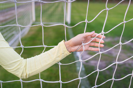 A girl stands near a white net close-up on a soccer field, a soccer goal. green fieldの写真素材