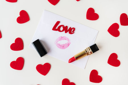 A white envelope with a lip print of red lipstick on a background of small red hearts. February 14 Valentine's Day conceptの写真素材