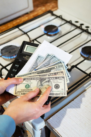 Payment of utility bills, calculations on a calculator. Euro and dollar bills lie near a burning gas burner. The concept of increasing the cost of natural gas supply and payment. Energy crisis, vertical photoの写真素材