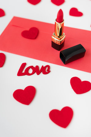 A red envelope with red lipstick on a background of small red hearts. The concept of the holiday February 14, St. Valentine's Dayの写真素材