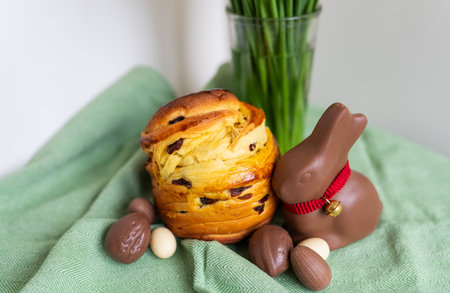Homemade Easter traditional pastries lie on a green napkin with a bouquet of flowers, a rabbit, chocolate eggs. Easter baking and decorationの写真素材