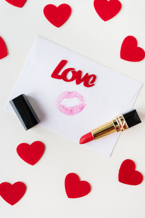 A white envelope with a lip print of red lipstick on a background of small red hearts. February 14 Valentine's Day conceptの写真素材