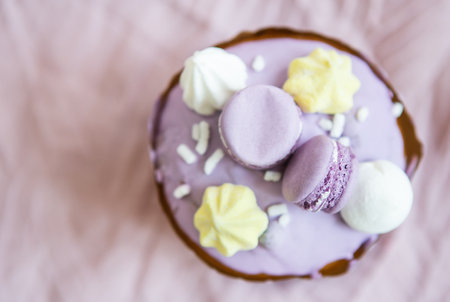 A traditional paska decorated with white Swiss chocolate and meringue stands on a lavender tablecloth. Easter holiday, top view. Place for descriptionの写真素材
