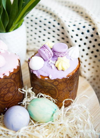 Colorful Easter eggs lie together with Easter pastries decorated with colored chocolate on a wooden tableの写真素材