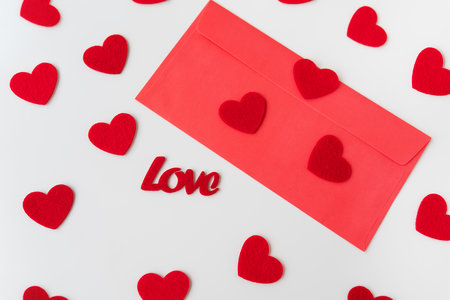 A love letter, the inscription of love on a red paper envelope on the background of small red hearts. The concept of St. Valentine's Dayの写真素材