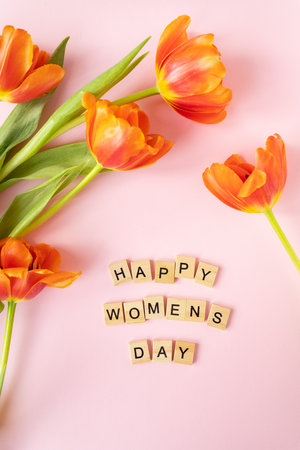 March 8, postcard. Happy Women's Day text sign on orange tulips background. Stylish flat lay with flowers and text, greeting cardの写真素材