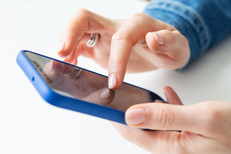 The girl is holding a smartphone in her hands. The concept of working online, freelancing, correspondence, chat. close-upの写真素材