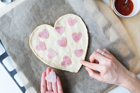 Heart shaped pizza dough, chef lays heart shaped sausage. Italian pizza, heart shaped pizzaの写真素材
