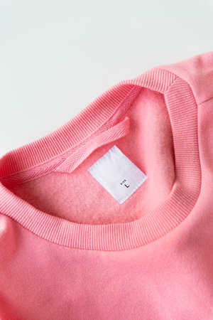 Clothing, fashion, shopping concept - closeup of a coral sweater tag. Place for inscription. Size L is written on the jacketの写真素材