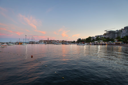 A very beautiful sunset on the pier, a beautiful sky in Budva, Montenegro against the backdrop of a pier with yachts and a resort townの写真素材