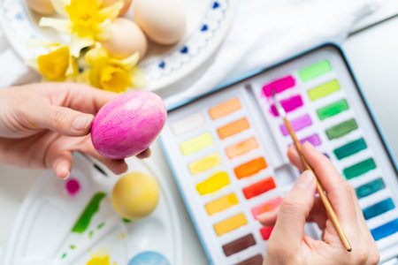 A brush in the process of painting Easter eggs with watercolors. The concept of preparing for Easter. View from aboveの写真素材