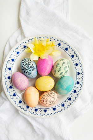 Easter eggs are painted in different colors and patterns on the plate. Top view, Easter celebration conceptの写真素材