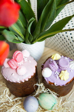 Colorful Easter eggs lie together with Easter pastries decorated with colored chocolate on a wooden table. easter holidayの写真素材