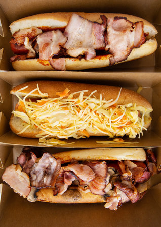 American hot dog with different flavors, with cheese and crispy onions on a white table in a minimalist style. Fast food, takeaway food, food for motorists. Hot dog sandwich with sausageの写真素材