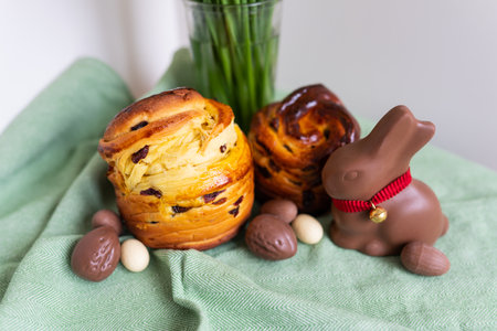 Homemade Easter traditional pastries lie on a green napkin with a bouquet of flowers, a rabbit, chocolate eggs. Easter baking and decorationの写真素材