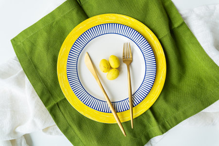 Festive table setting with bright napkins and yellow and blue plates with utensils and yellow chocolate eggs. beautiful table designの写真素材