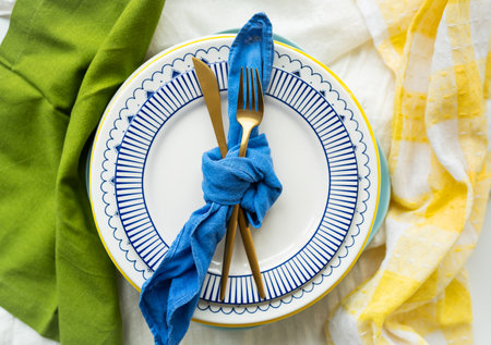 Gold cutlery is tied with a blue napkin, on which the plates are on a green-yellow linen napkin. Minimalist design, rustic. Birthday or wedding celebration. Serving designの写真素材