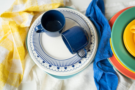 A pyramid of brightly colored bowls, plates and cups of different sizes and colors on the kitchen table. Scandinavian style, minimalism. View from aboveの写真素材
