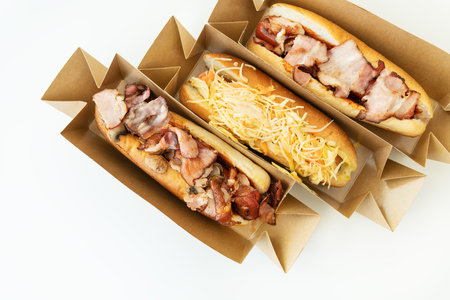 Delicious hot dog grilled in a restaurant, homemade hot dogs wrapped in bacon, with onions and mushrooms, salad. Street food, delivery, takeout, food for the car, food for travelの写真素材