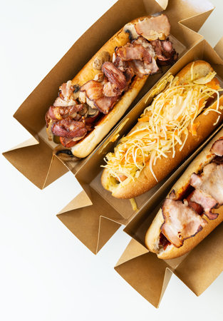 Delicious hot dog grilled in a restaurant, homemade hot dogs wrapped in bacon, with onions and mushrooms, salad. Street food, delivery, takeoutの写真素材