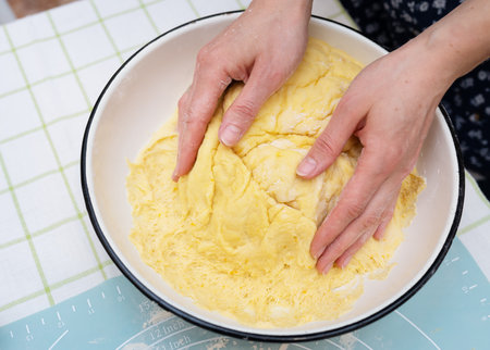 A woman kneads dough with her hands, a baker, baker's hands, dough, hands in flour, handmade baking. View from aboveの写真素材