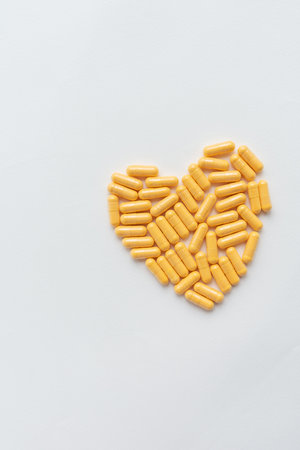 Yellow pills in the shape of a heart, health and heart problems. The concept of medicine and healthcare. Place for an inscription, vertical photoの写真素材