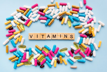 Different colorful pills from different symptoms in the middle - the inscription from wooden letters vitamins. health and medicine conceptの写真素材