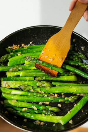 Close-up of healthy frying asparagus with salt and garlic in a frying pan. Delicious and healthy foodの写真素材