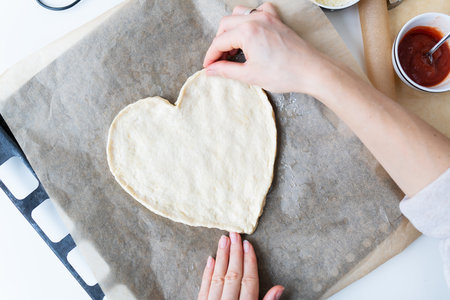 Pizza in the shape of a heart. Romantic valentine's day menu concept for restaurant or deliveryの写真素材