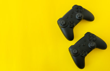 Isolated game joysticks on a yellow background. Gamer playing at home, relaxing with friends, competitionの写真素材