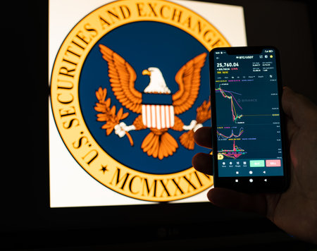 Kyiv, Ukraine - 06 June 2023: Man holds a smartphone with falling Bitcoin chart on Binance against the background the SEC . SEC Accuses Binance of Mishandling Funds and Lying to Regulatorsのeditorial素材
