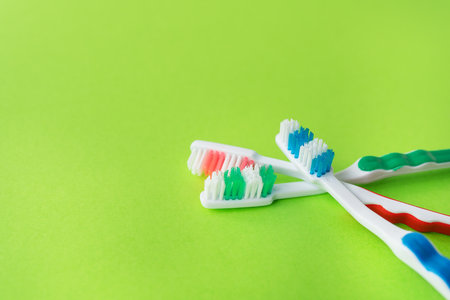 Multicolored toothbrushes on a green background, the concept of dental care and oral hygiene. Place for an inscriptionの写真素材