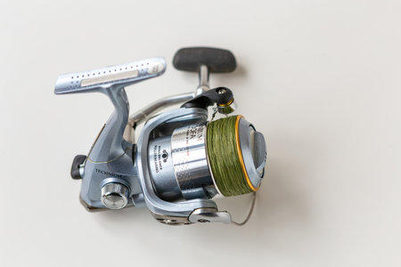 Kyiv, Ukraine - 27 January 2023: Blue steel fishing reel with cord wound on a spool on a white background. Shimano Technium it is a pro fishing tool of medium price level for enthusiastic fishermenのeditorial素材
