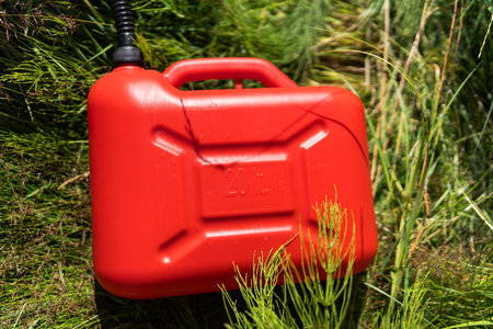 Red plastic canister among the green grass. Problems on the road with fuel for the car. high quality photoの写真素材