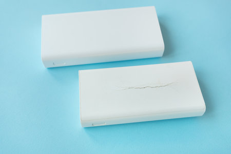 Two power bank new and old with a crack on the case. An old battery that has become unusable expands and swells until the case breaksの写真素材