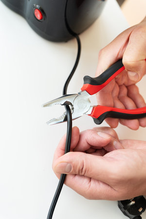 A man sits at a table and makes repairs to small household appliances, repairs with a screwdriver. close-upの写真素材