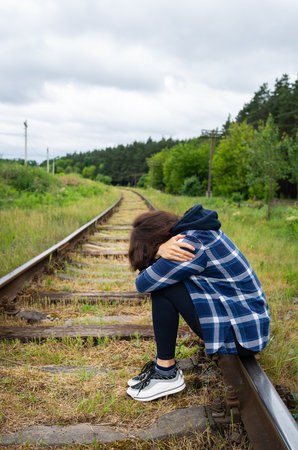 Stress, sadness, loneliness, pain. An upset girl sits on the rails, a psychological situation, help...