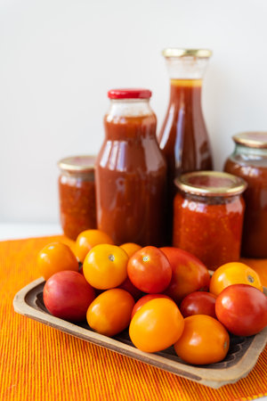 The process of preserving pickled tomatoes and peppers in glass jars on the table. Adjika, spicy-sweet vegetarian sauce for dishesの写真素材