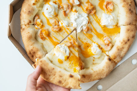 In your hands is a piece of juicy hot pizza. Italian pizza with seafood, shrimp and a lot of cheese. Home delivery, fast foodの写真素材