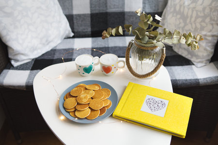 Two cups of coffee and delicious pancakes stand on the table, yellow photo album.の写真素材