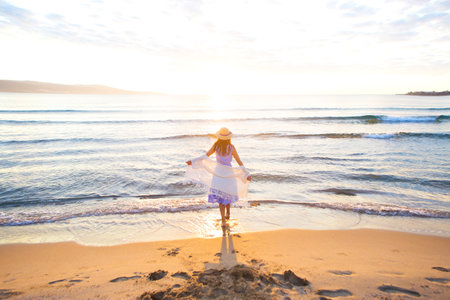 happy beautiful girl in dress and hat runs to meet the sun.の写真素材