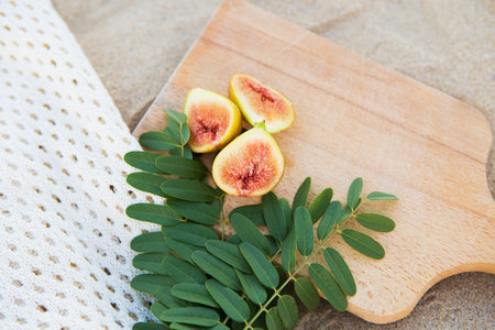 cut figs on a wooden board near the sea.の写真素材
