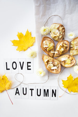 baked pears with brie cheese and nuts on a background of autumn yellow leaves, the inscription love autumn.の写真素材