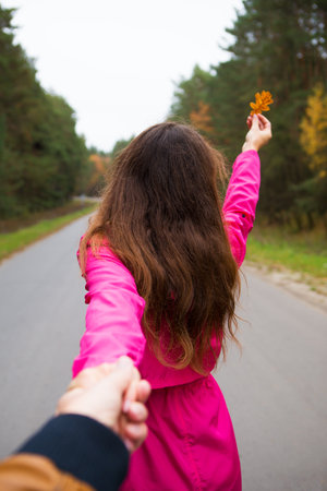 the girl is standing on the road holding a yellow leaf.の写真素材